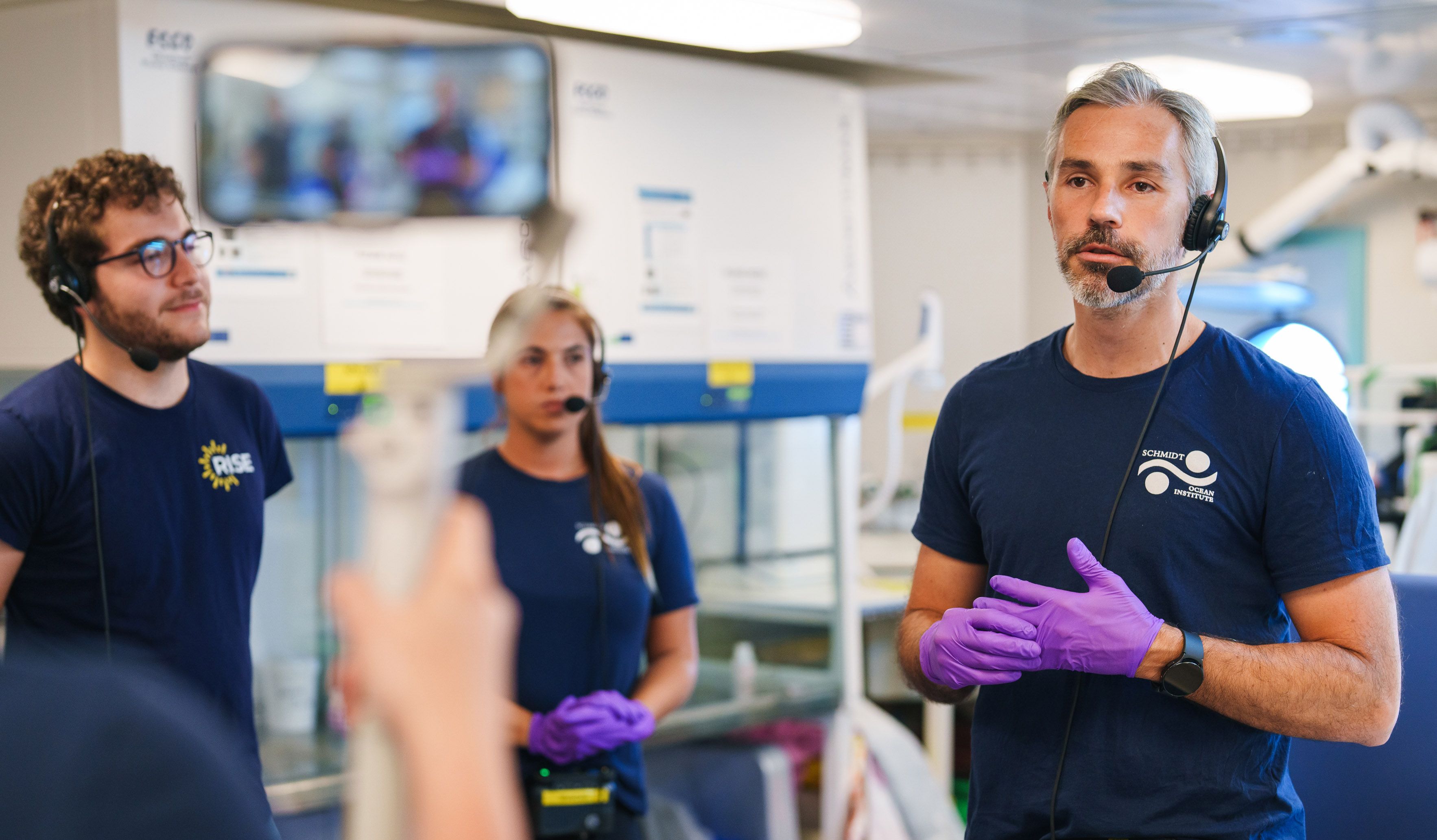 Presenters in a laboratory on the ship during a ship-to-shore video broadcast.