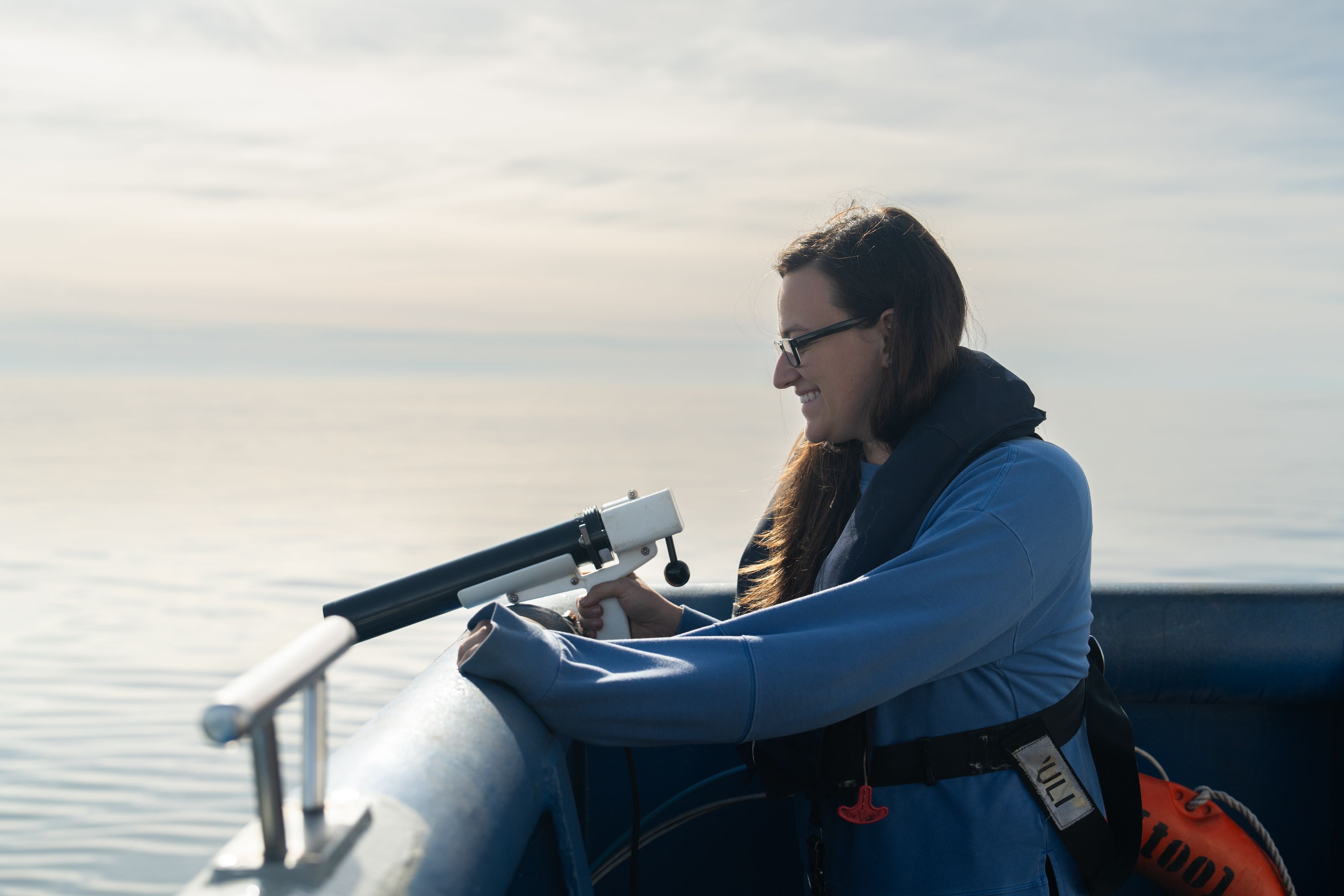 A smiling technician deploying an XBT probe off the stern of the ship.