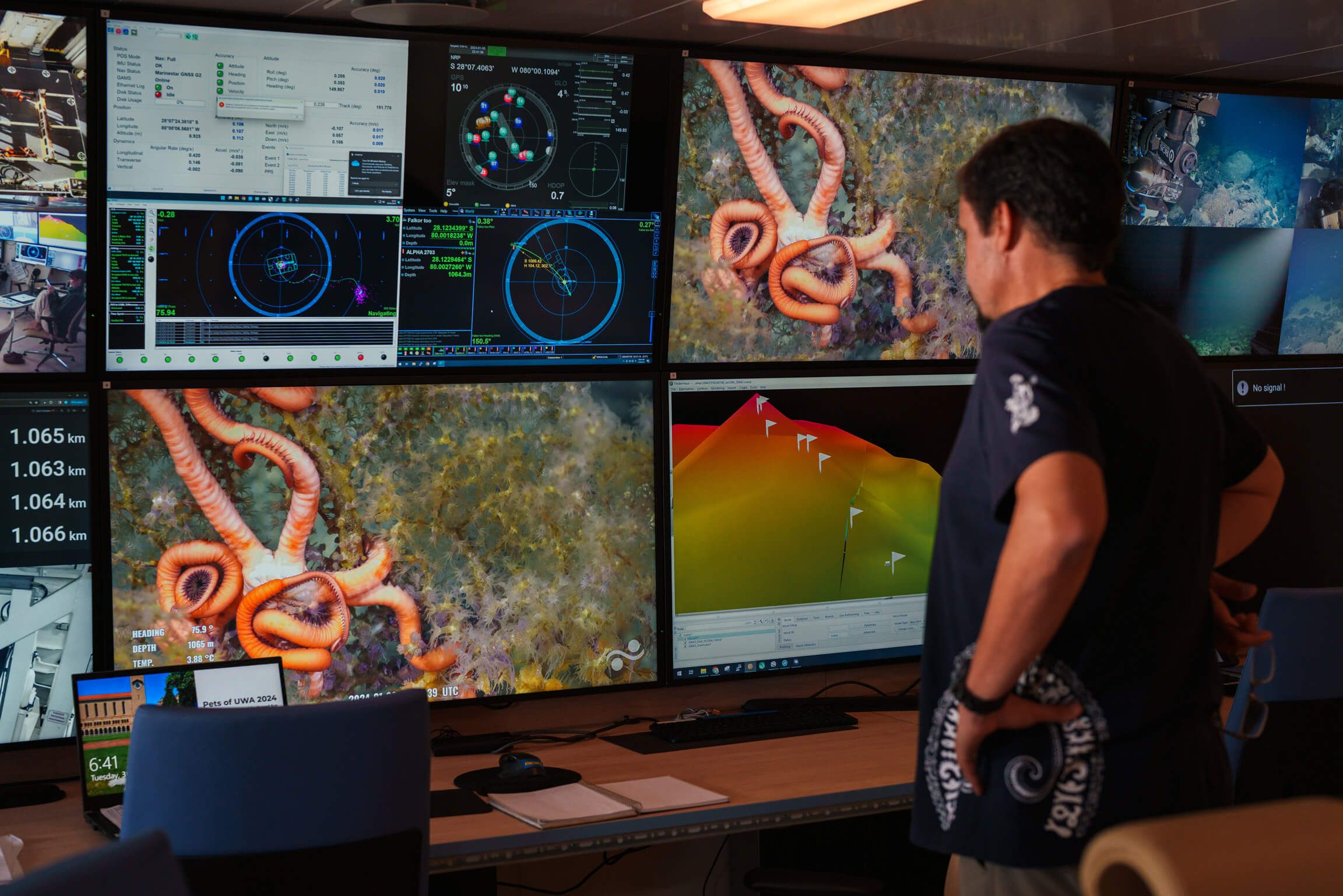 Scientist assessing 8 large screens showing metrics, images, and other data