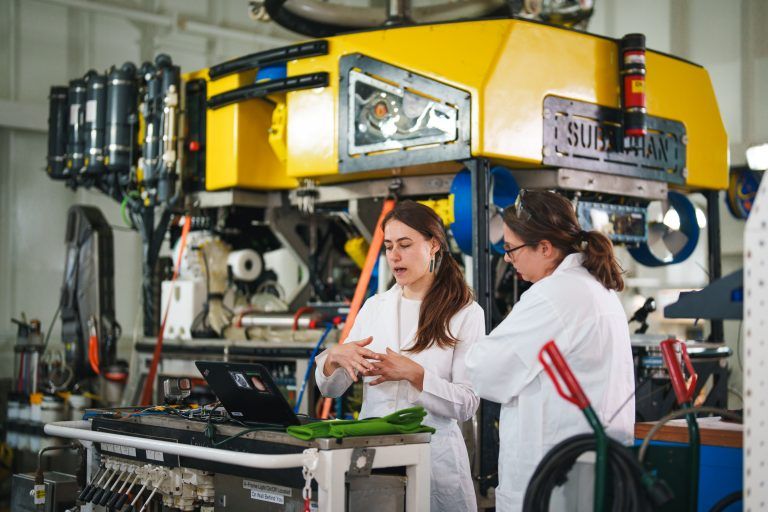 Scientists standing in front of an underwater rover