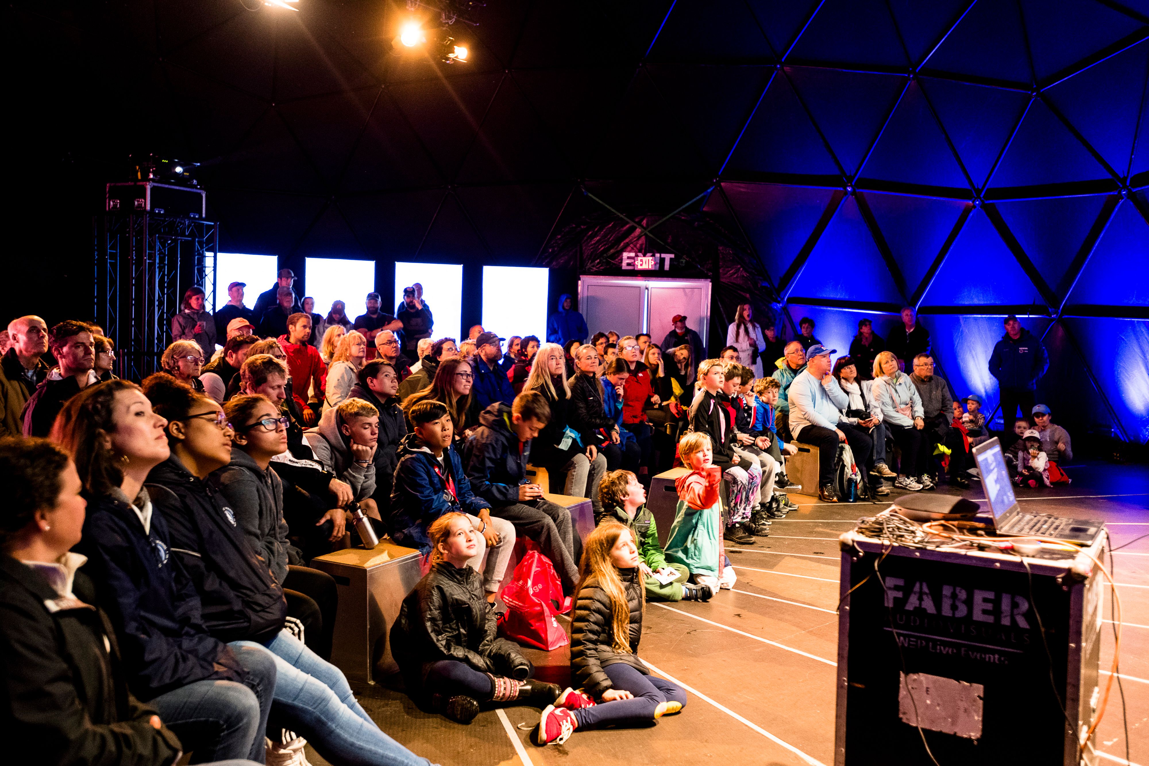 Children and families watching a projection of a conversation