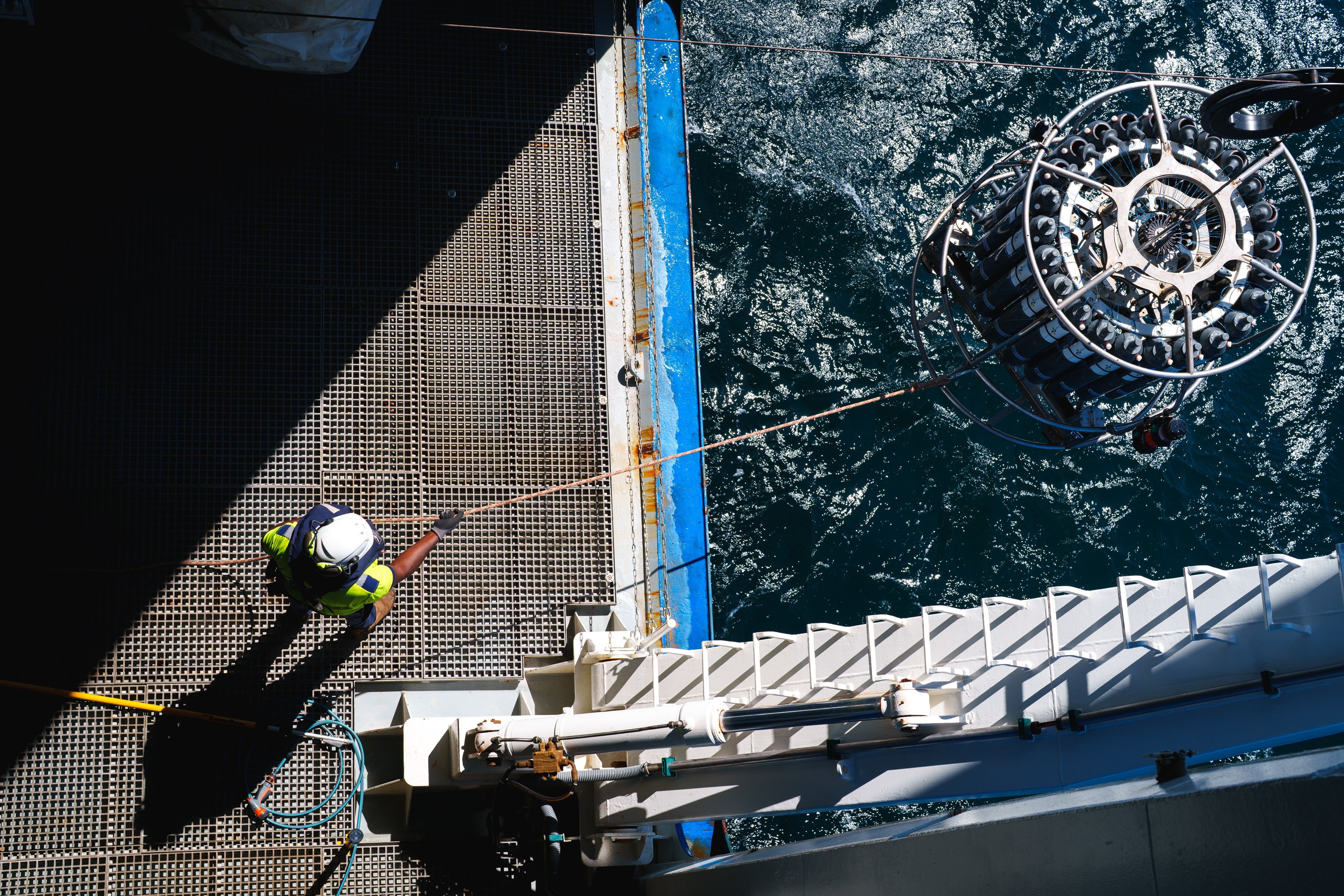 A top down view from the hanger of Falkor (too) showing the CTD being deployed with the bosun handling a tagline on the rosette.