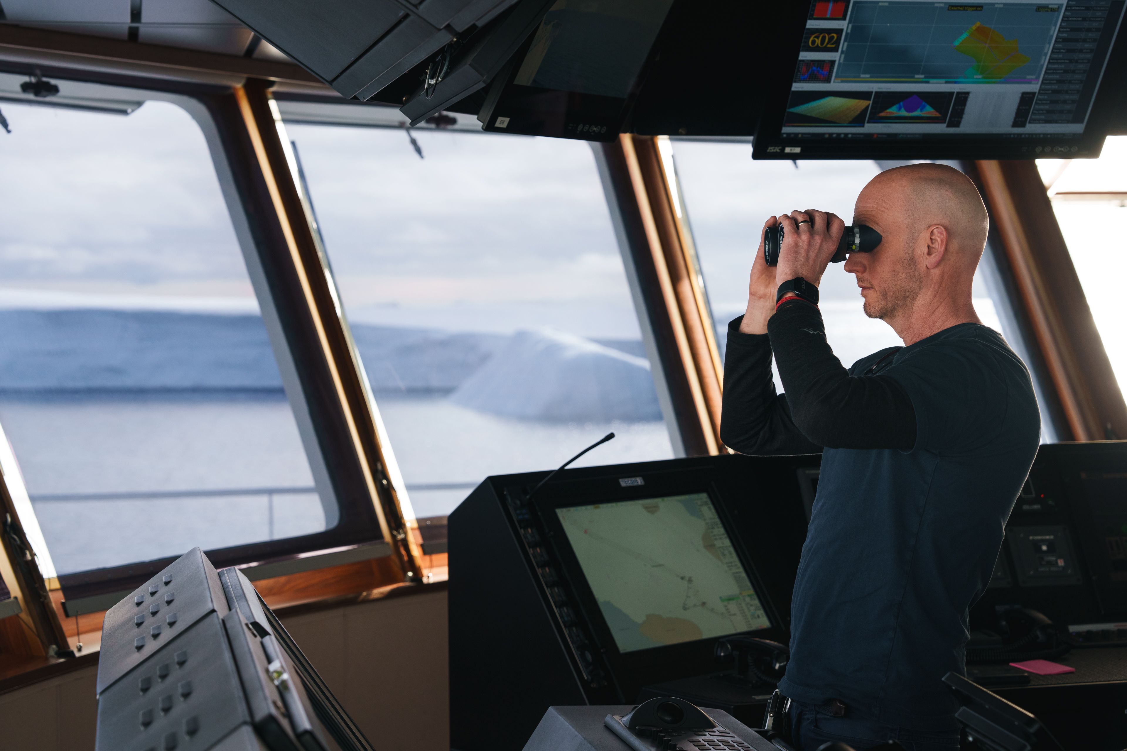 Person looking over deck of a ship with binoculars