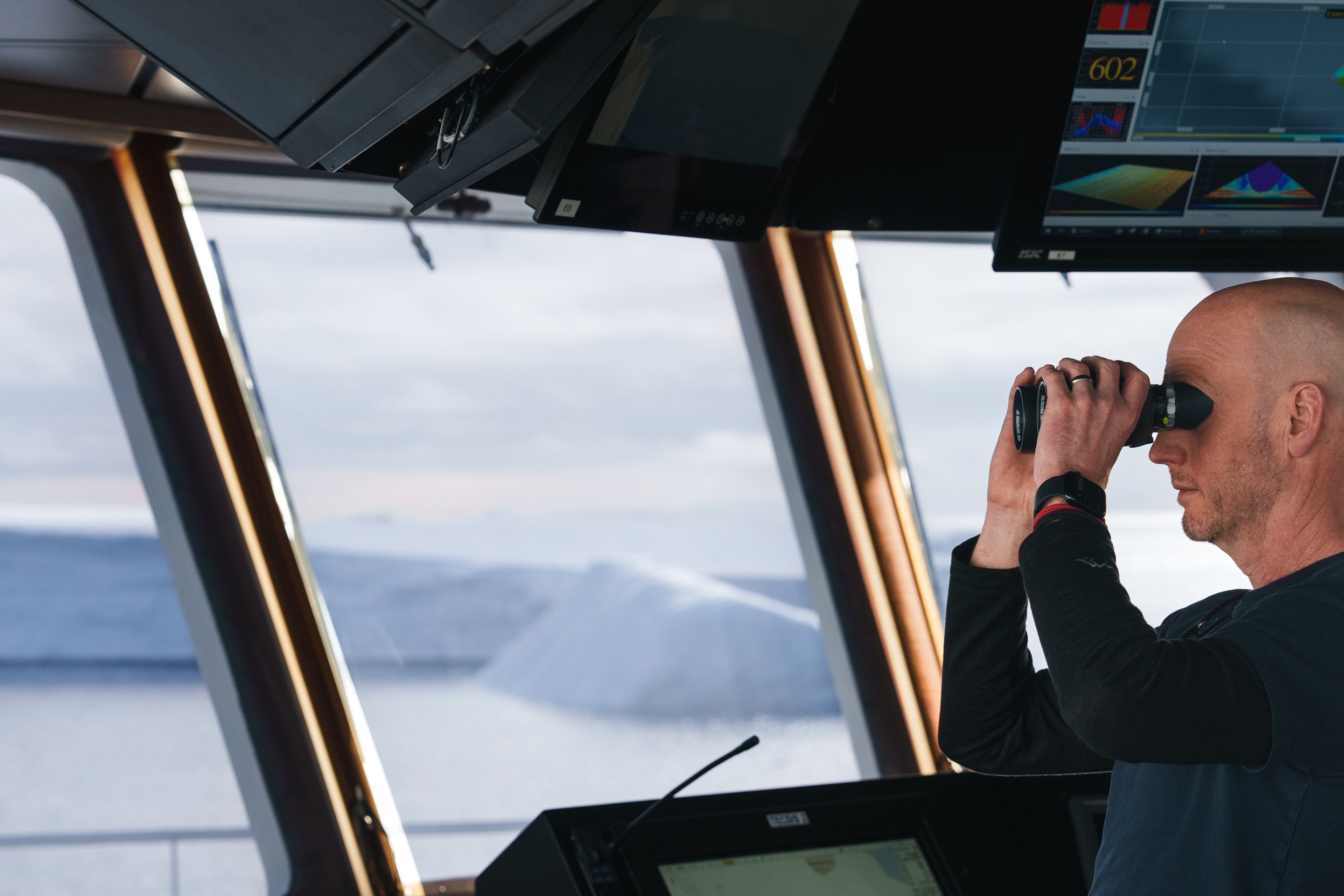 Person looking over deck of a ship with binoculars