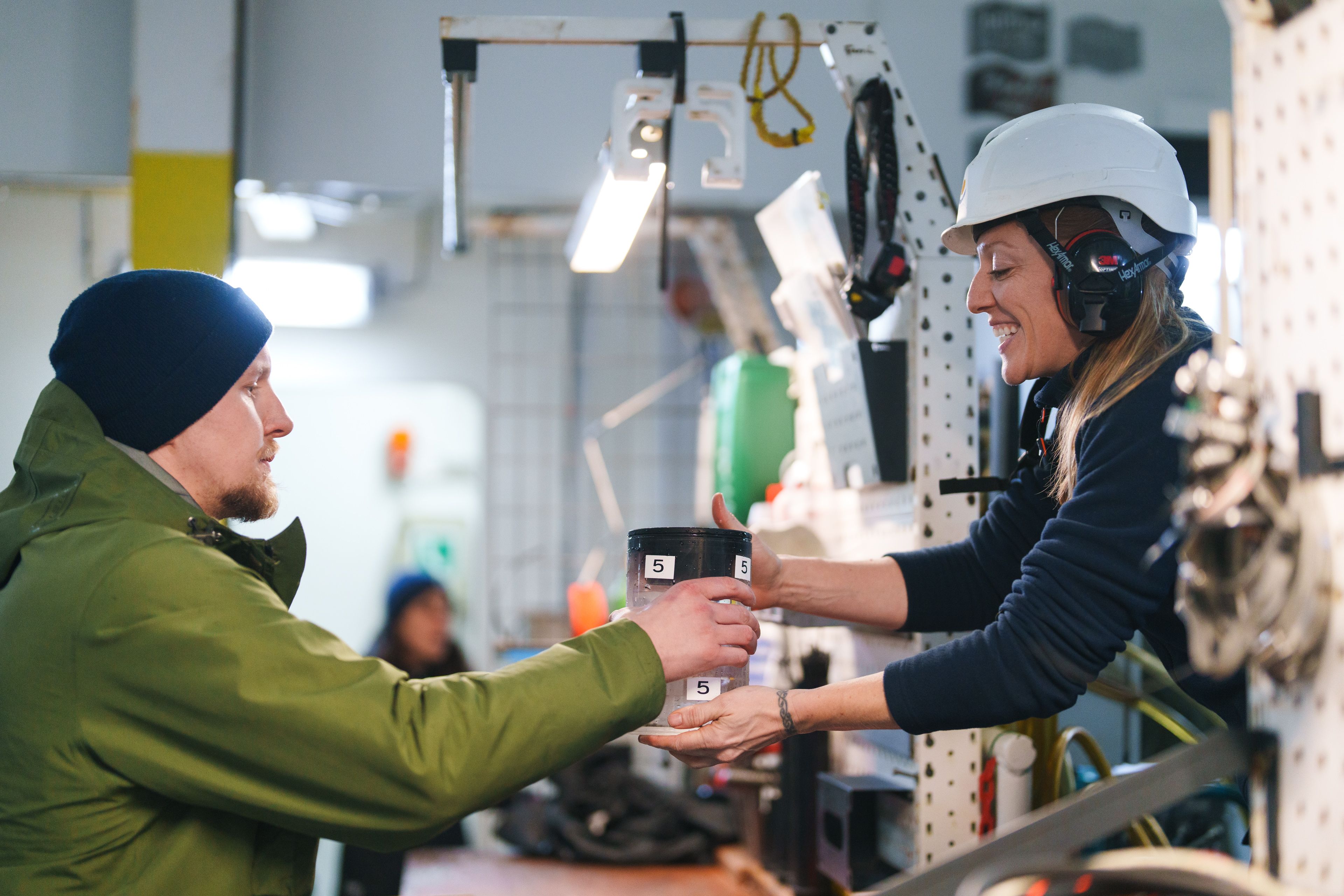 ROV pilot hands scientist sample after a dive.