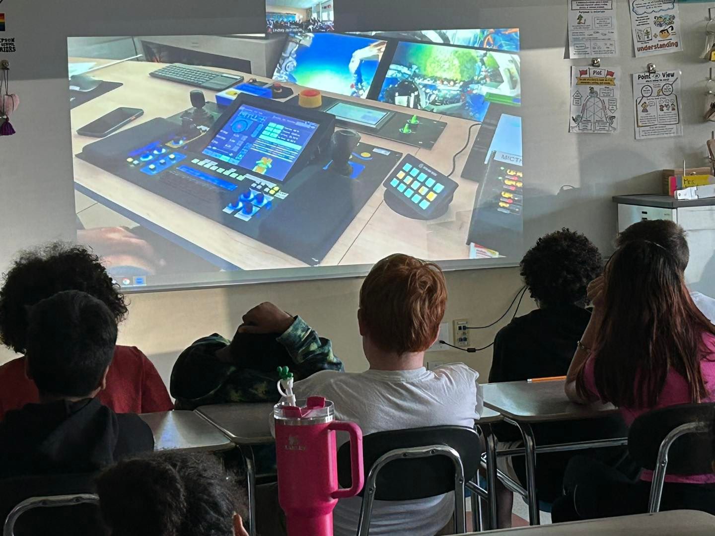 Young children siting at desks watching overhead projector presentation