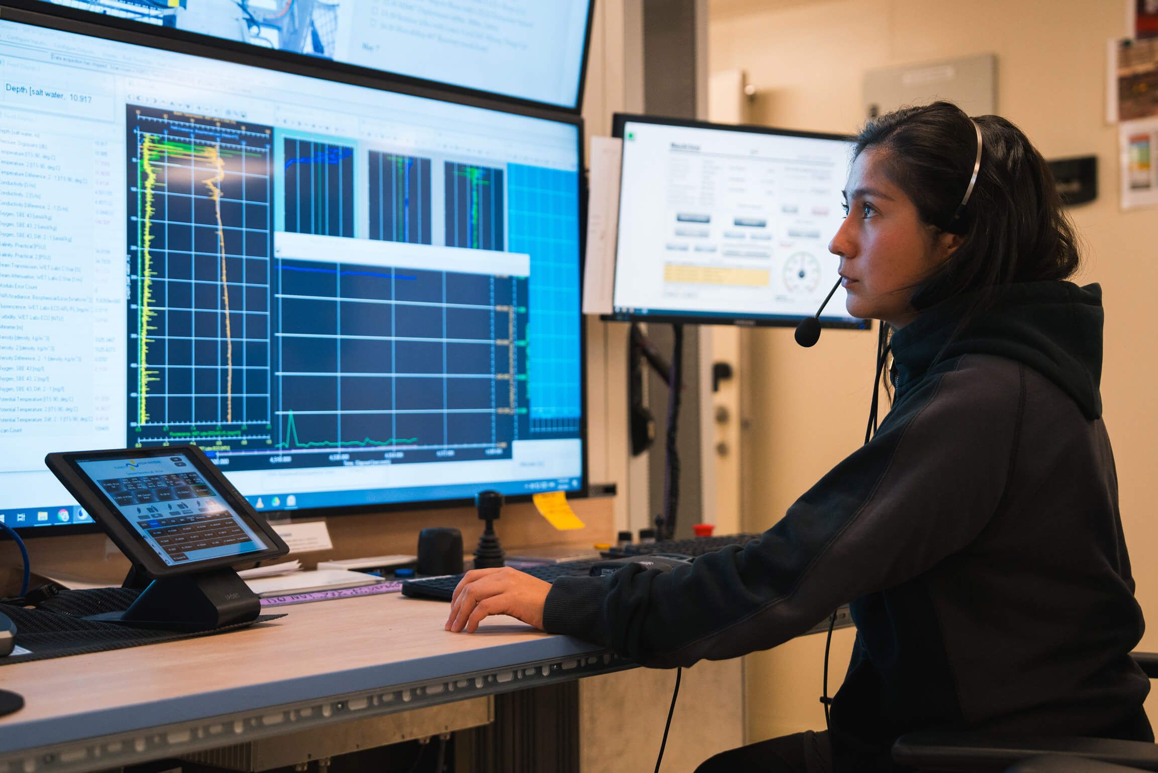 Scientist wearing headset looking at three monitors