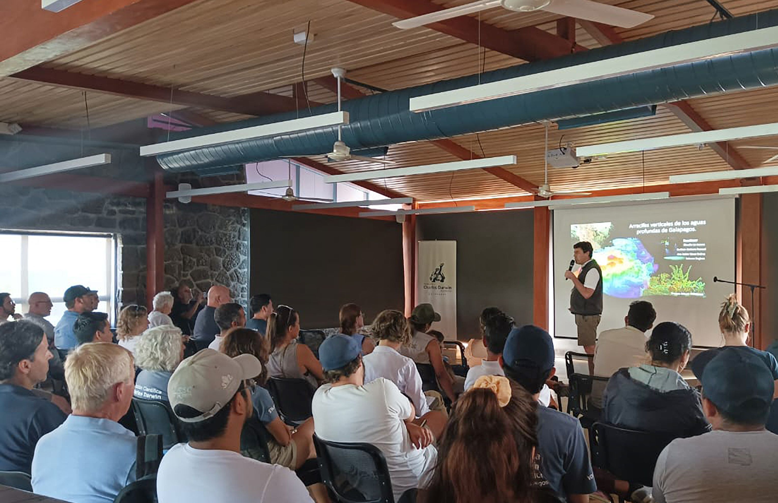 group of people watching a presentation on screen while someone talks 