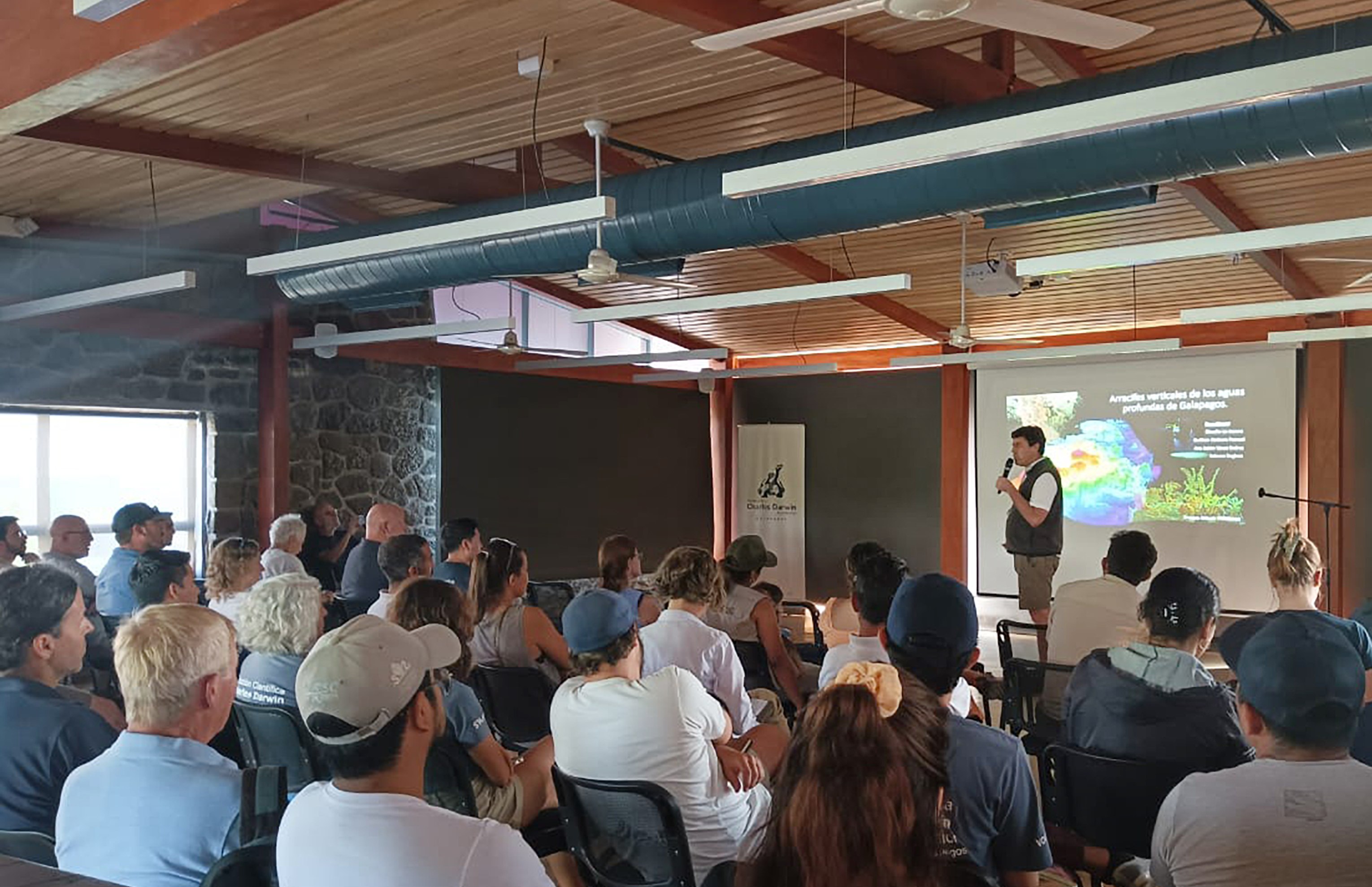 group of people watching a presentation on screen while someone talks