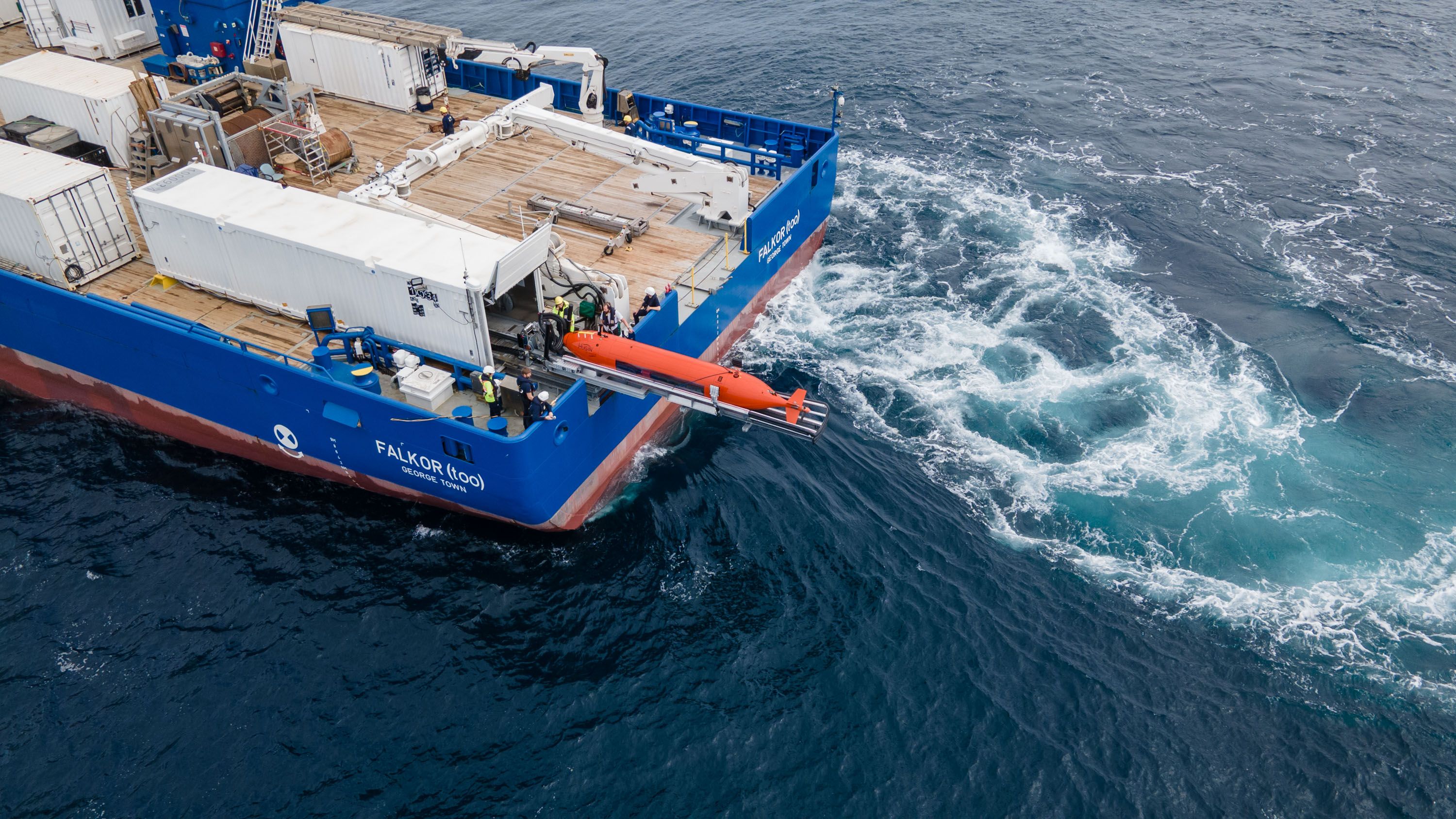 Aerial view of the AUV being launched off the RV Falkor (too) with lots of thruster wash from the ship. 