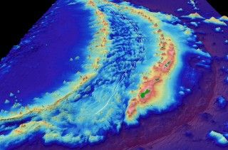 Computer-generated view of the seafloor in the Mariana back-arc (white line) where R/V Falkor discovered 4 new hydrothermal vent fields and a recent volcanic eruption. The Mariana trench is in the lower right (in purple) and the island of Guam is in the middle right (in green).