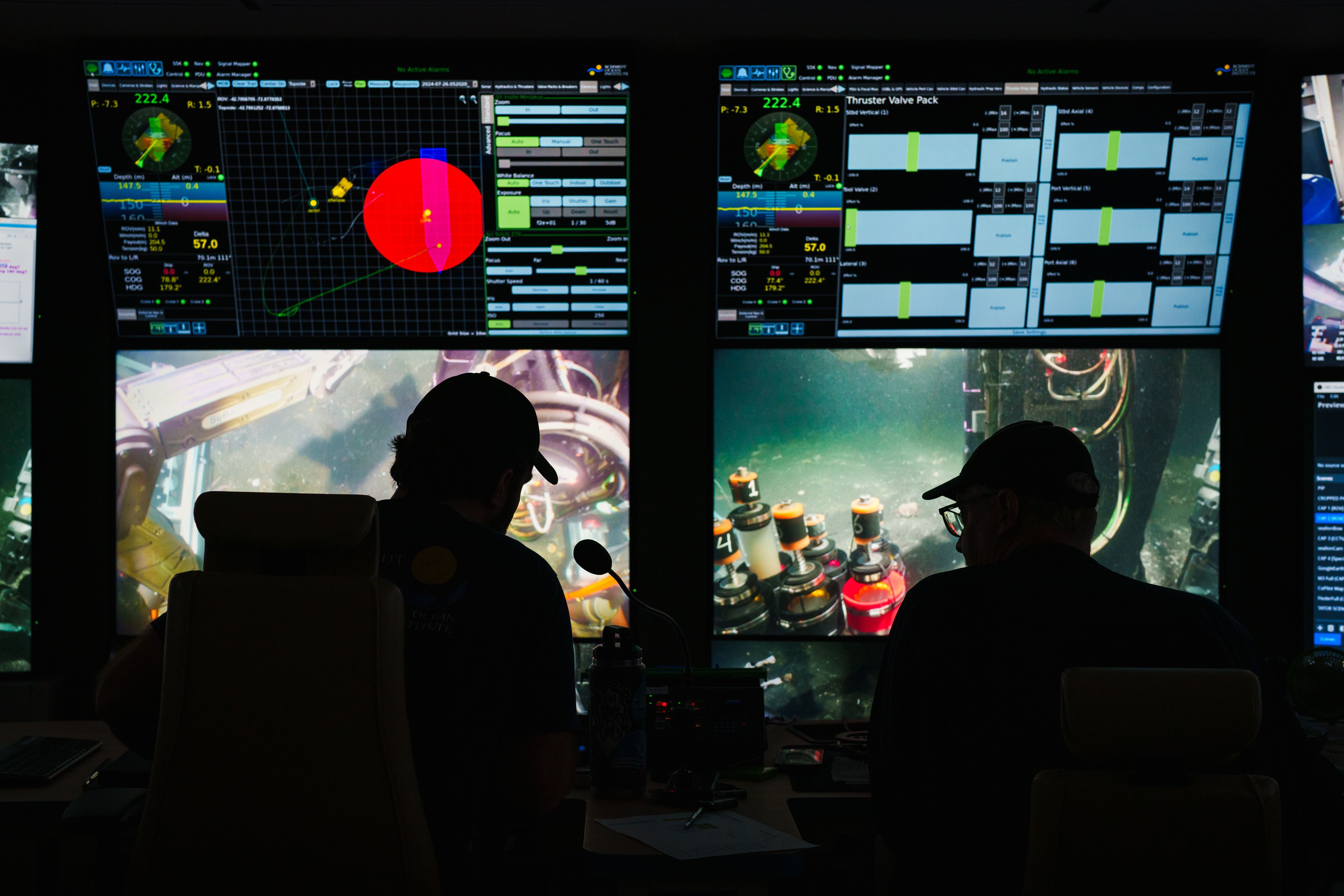 A view of mission control showing pilot screens with the pilots silhouetted in front of the screens.