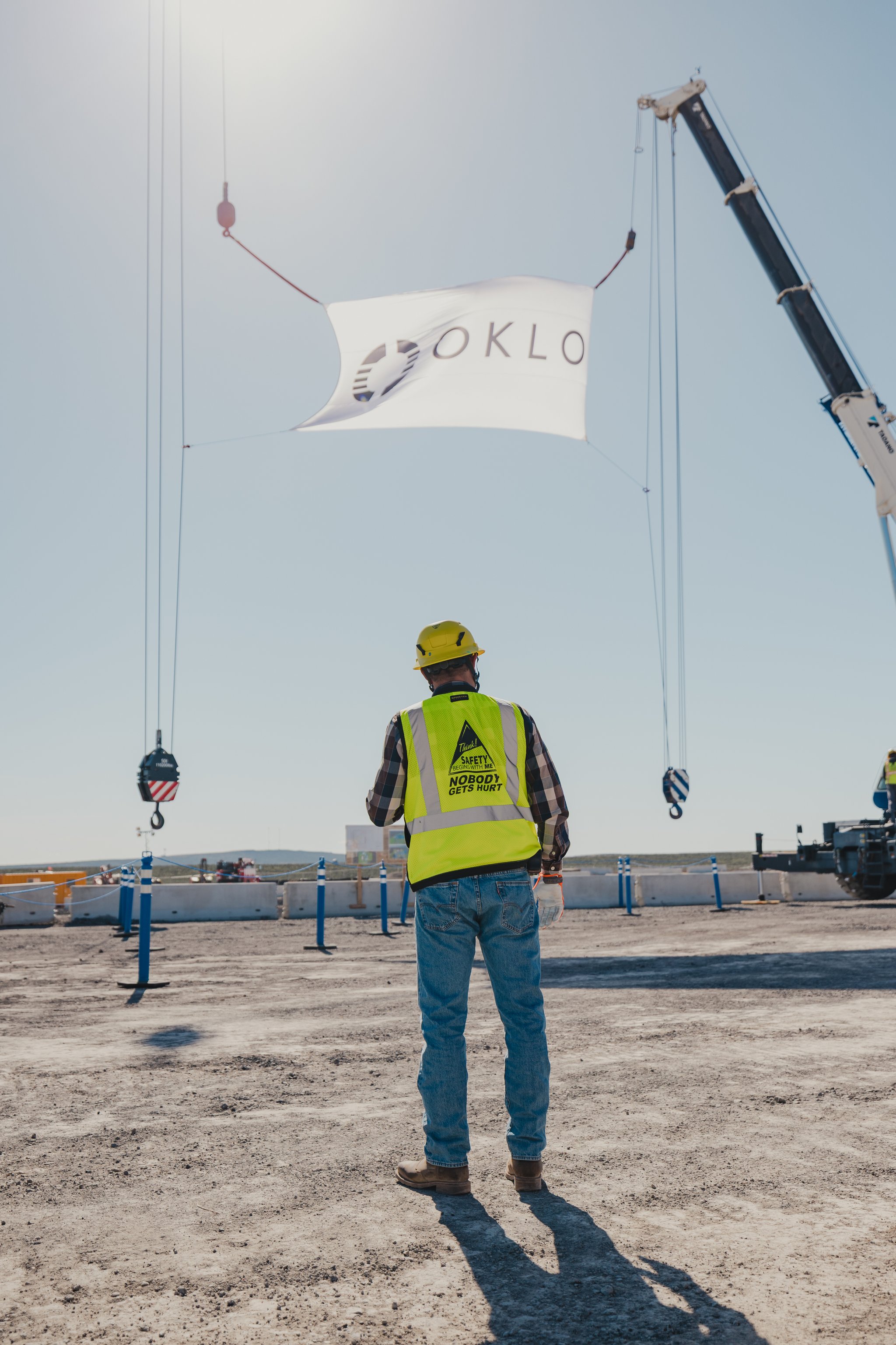 Oklo worker raising a flag at the Aurora construction site