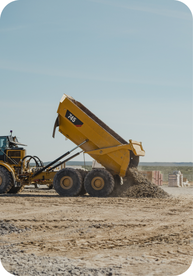 Yellow dump truck tipping soil at the Aurora site