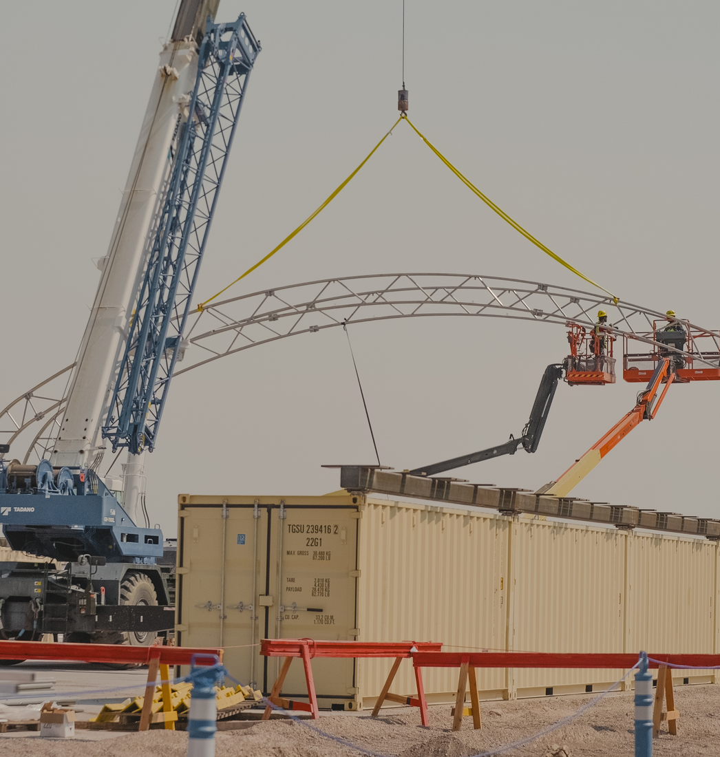 Crane lifting a structure over a shipping container at the Idaho site