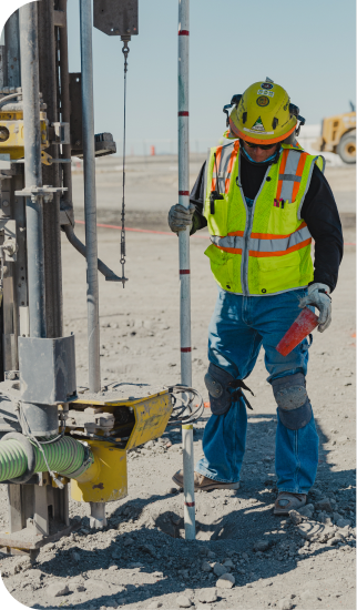 Surveyor beside a drill rig on the Aurora site