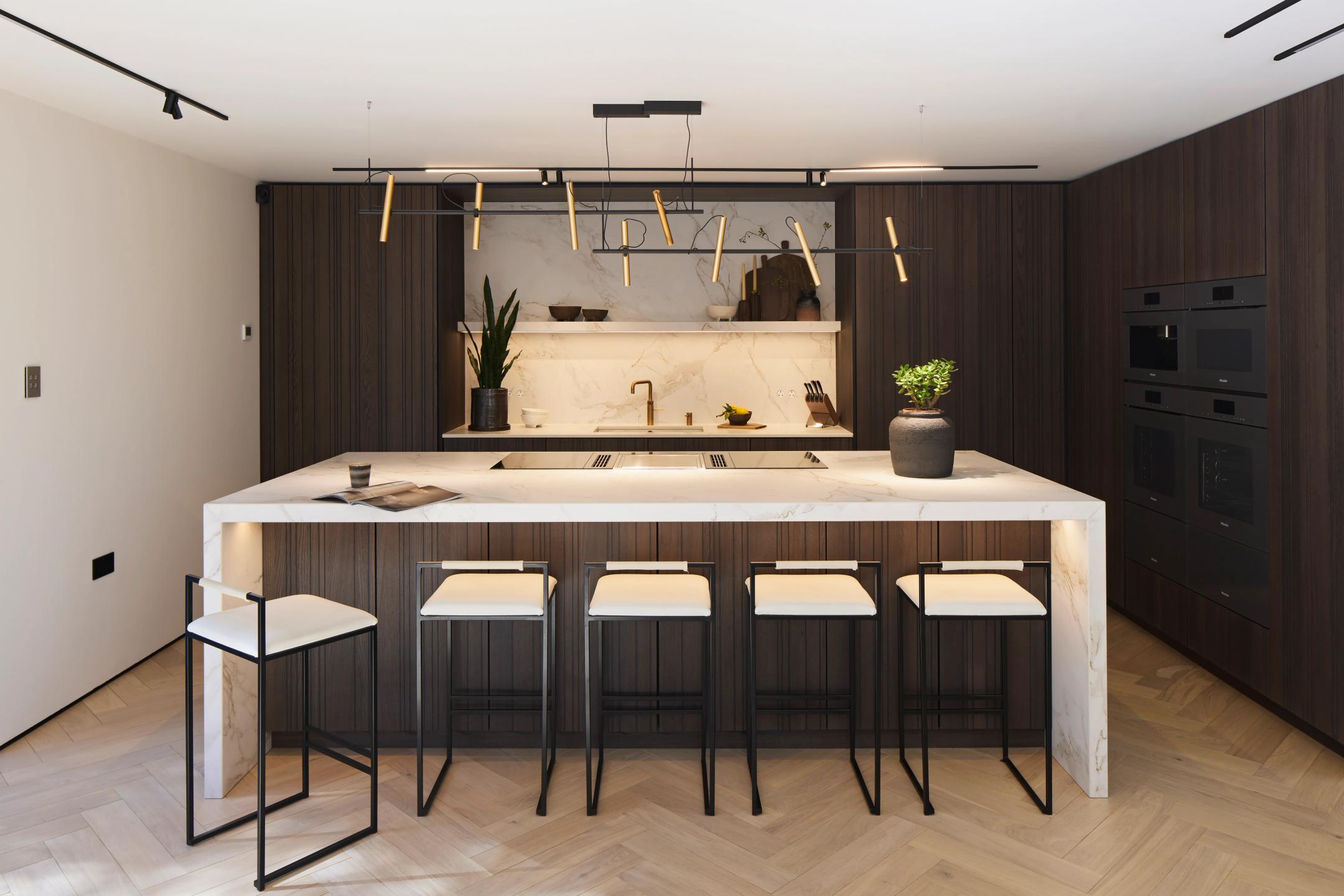 Leicht Bahia veneered door, Dekton Entzo worktops and floating shelf, waterfall ends island and full suite of Miele appliances in this striking modern kitchen
