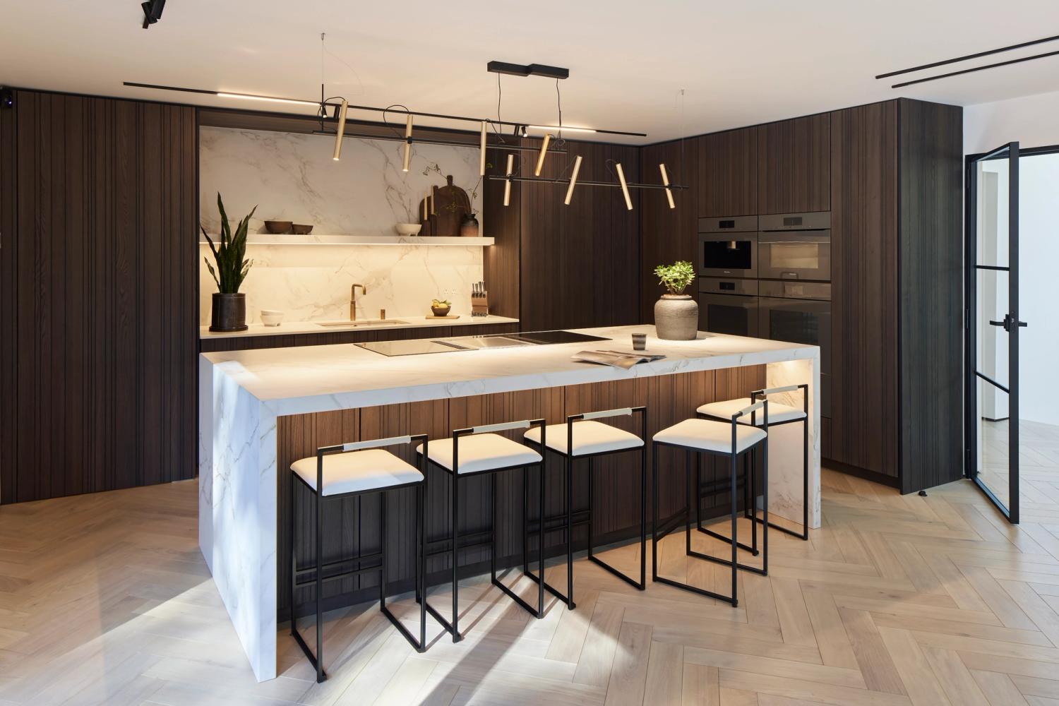 Leicht Bahia veneered door, Dekton Entzo worktops and floating shelf, waterfall ends island and full suite of Miele appliances in this striking modern kitchen