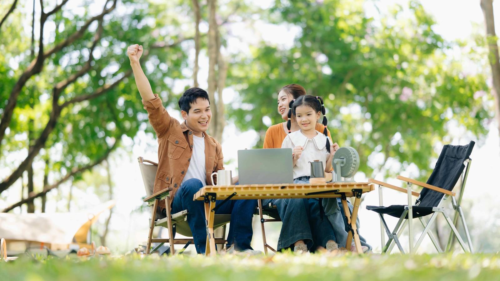 Family relaxing outdoors with a laptop
