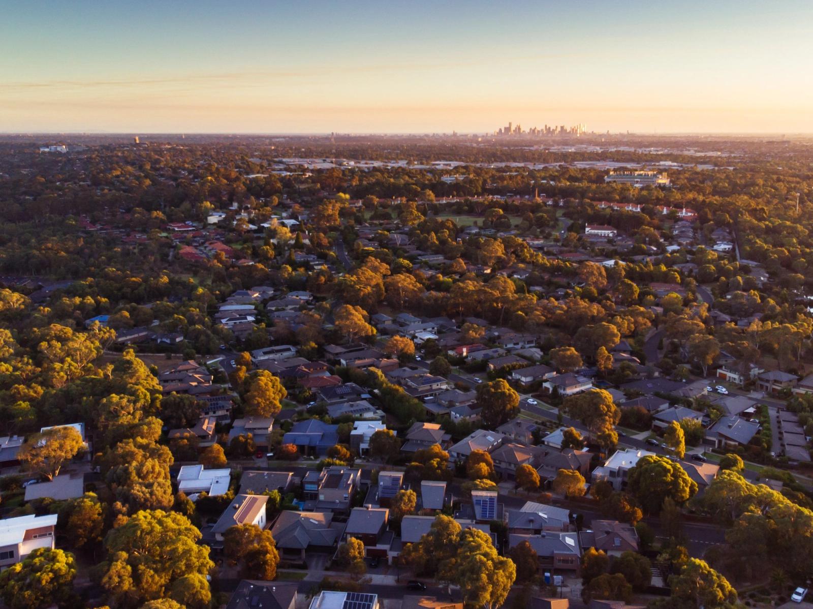 Aerial view of suburban homes with Melbourne skyline at sunset