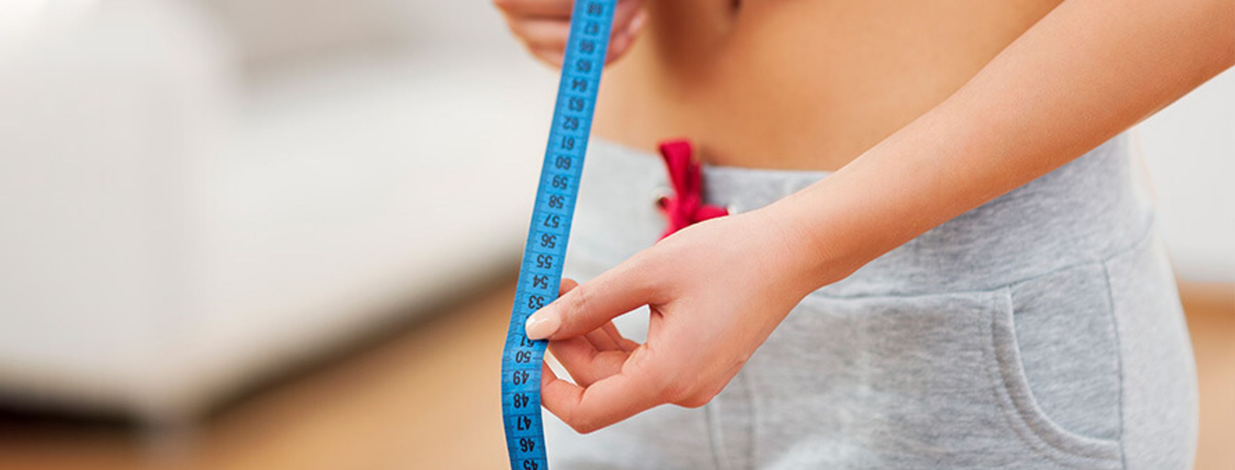 A woman measuring her waist with a tape measure