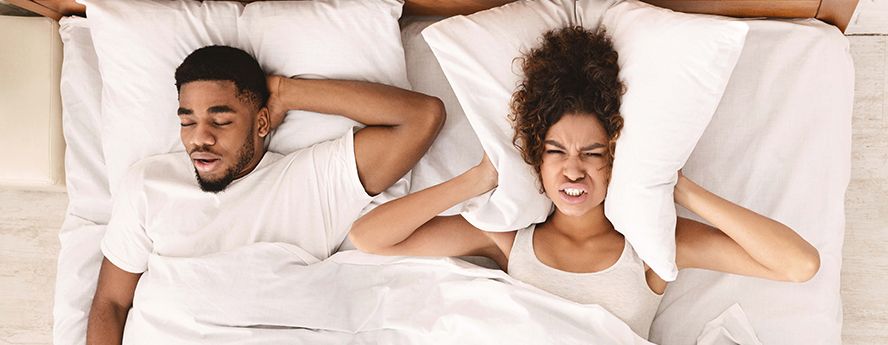 A man and a woman lying in bed trying to sleep