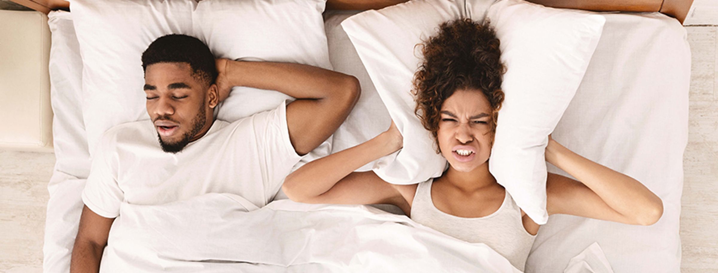 A man and a woman lying in bed trying to sleep
