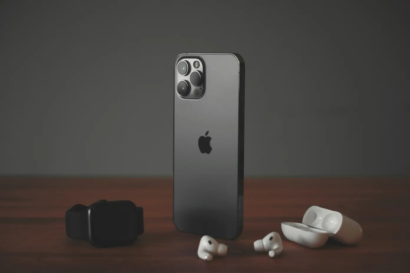 iPhone 12 Pro Max na stole spolu s AirPods Pro a Apple Watch Series 4