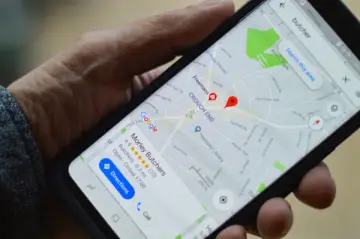 Mobilní telefon držený rukou s otevřenými Google Mapami, na kterých je vyznačena lokalizace.