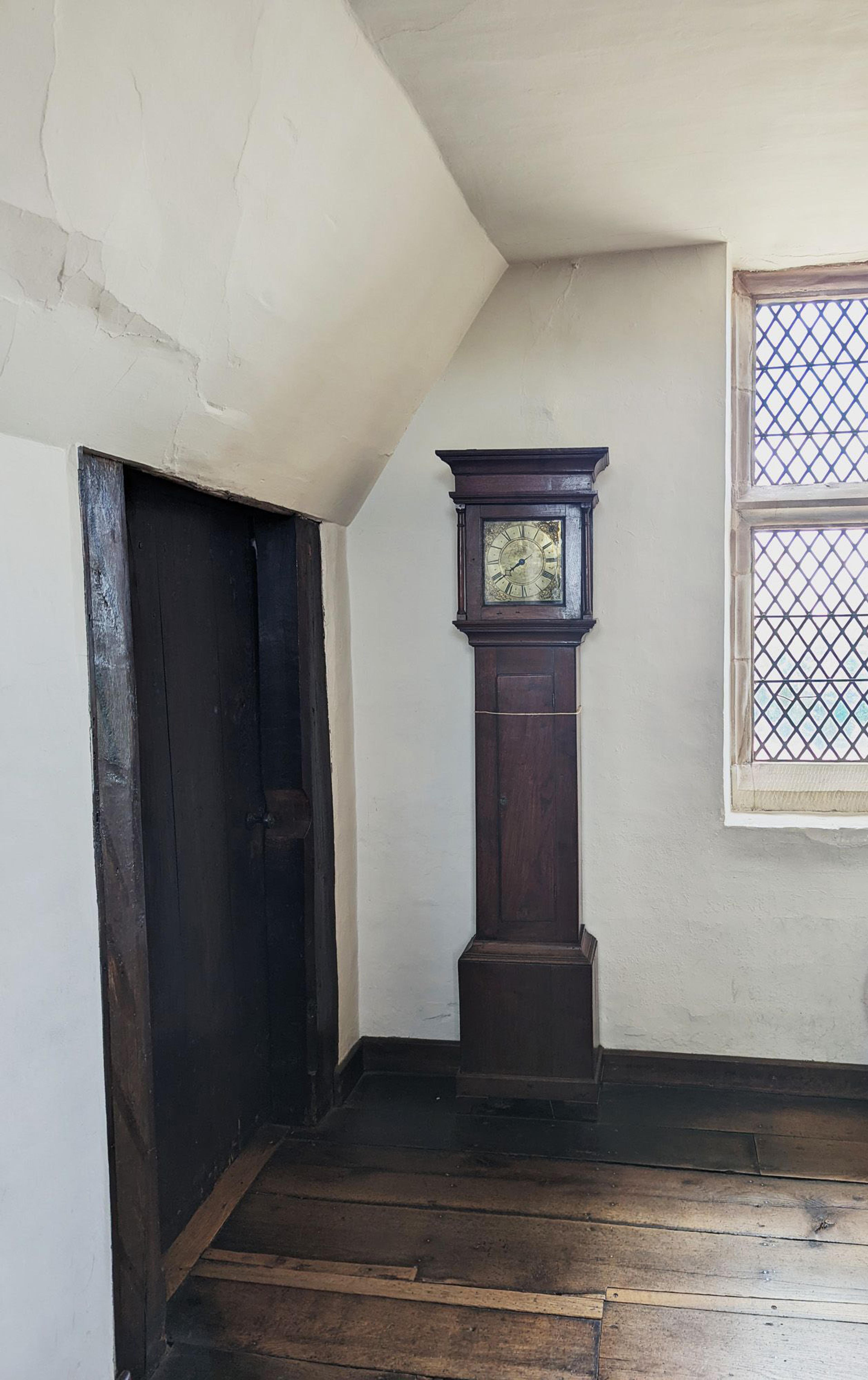 A small door to the left of a longcase clock