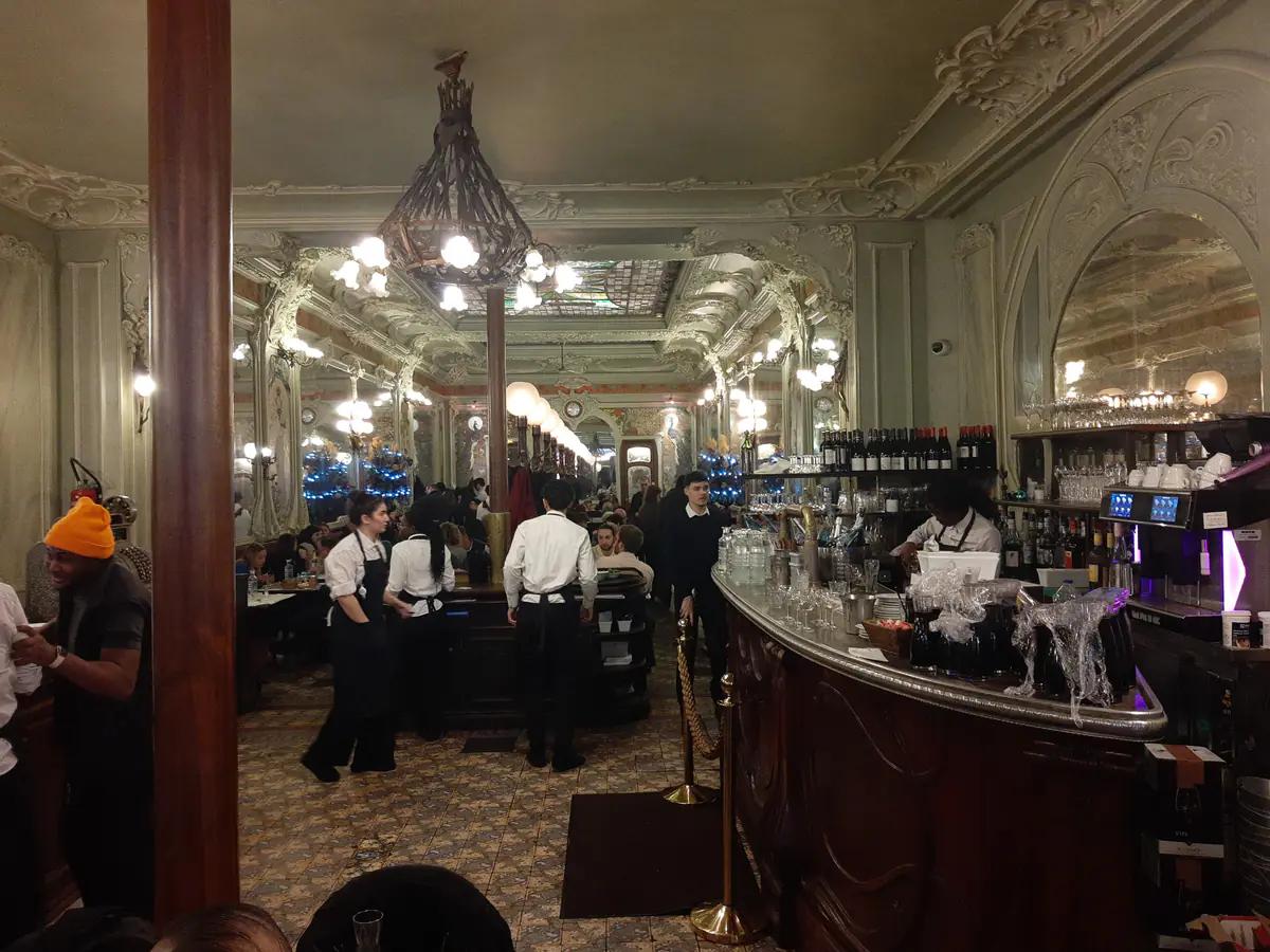 Avizeli, kalabalık bir restoran salonunda servis yapan garsonlar ve bar tezgâhı