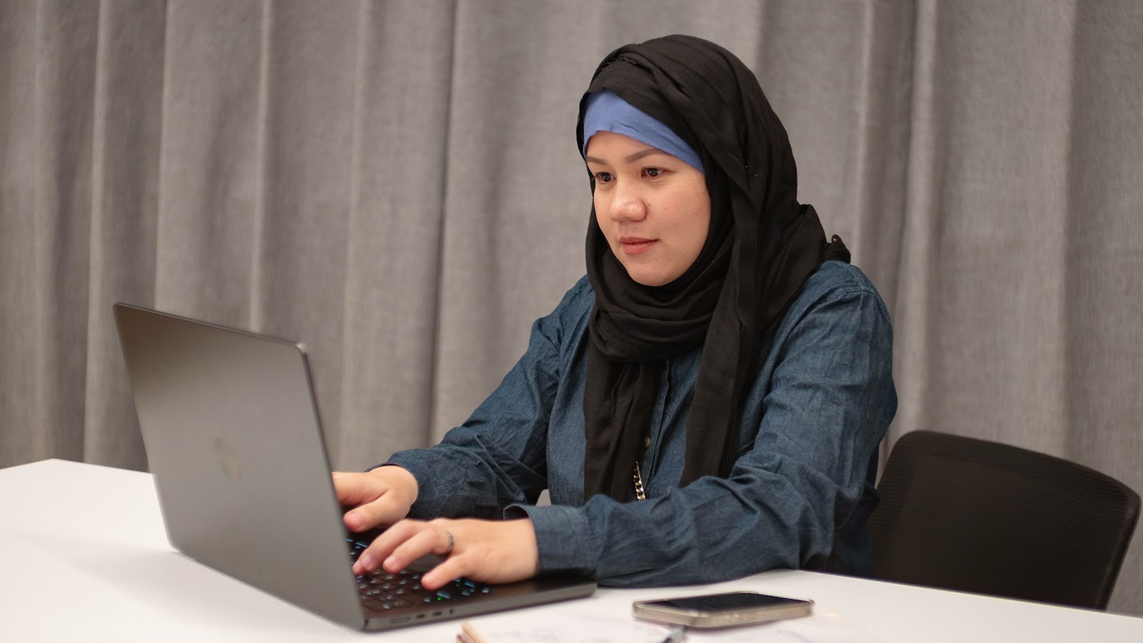 Team member concentrating on a laptop at a meeting table