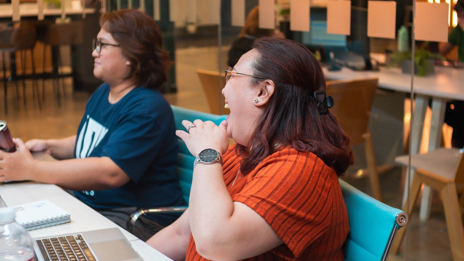 Colleagues listening and working on laptops during a session