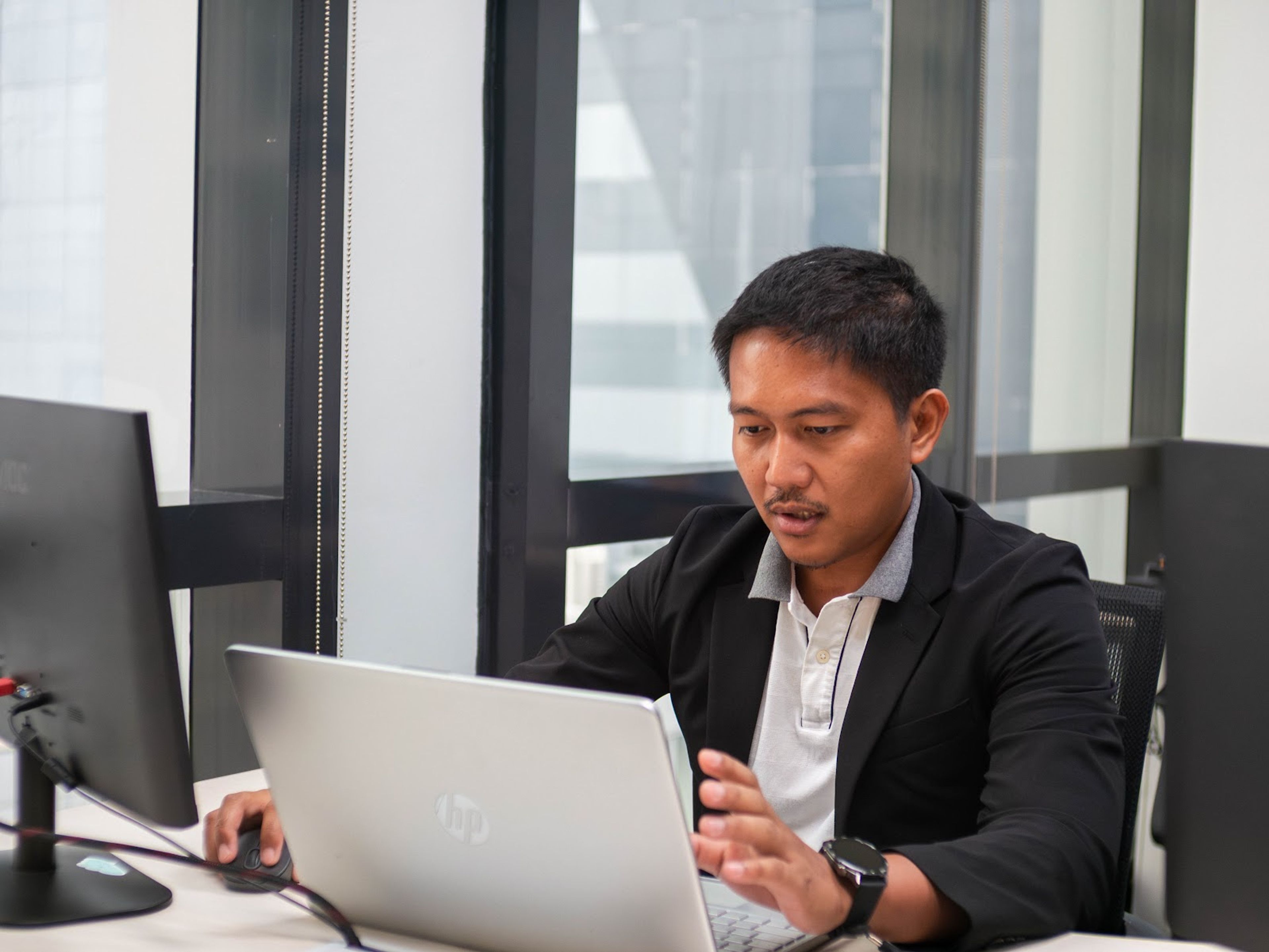 Team member working on a laptop by an office window