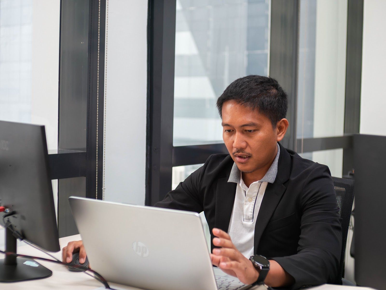 Team member working on a laptop by an office window