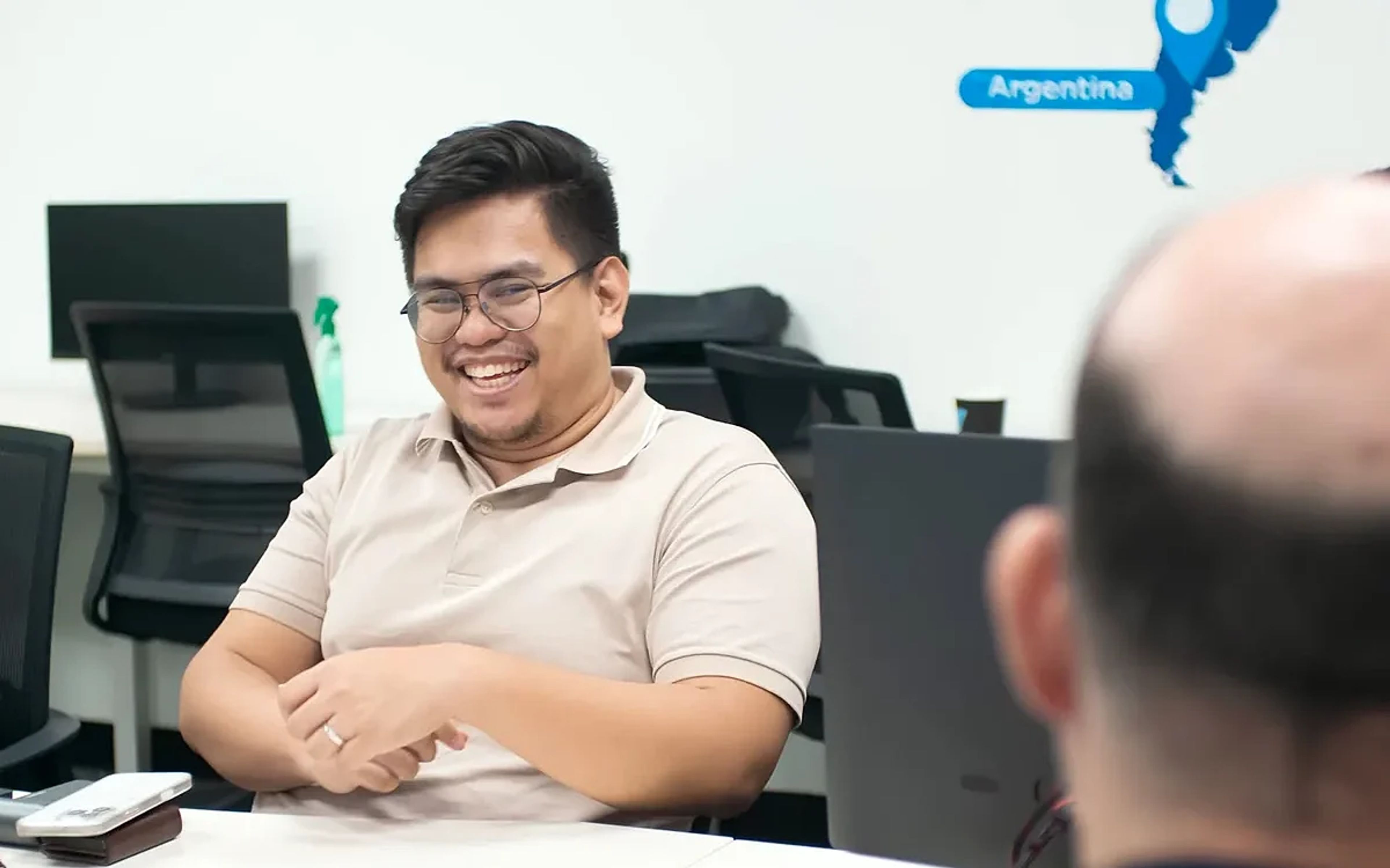 Cloud Employee team members smiling around a meeting table with company values displayed on the wall