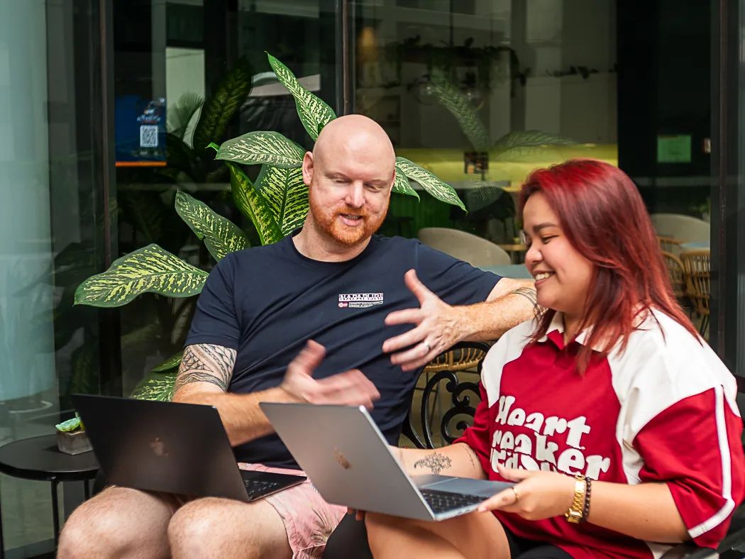 Cloud Employee team smiling and gesturing while collaborating on laptops in an outdoor office terrace