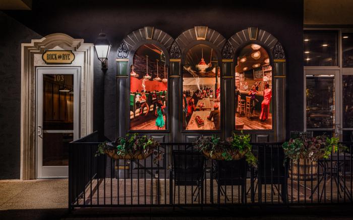 The Rock and Rye patio at night, lit from the bar’s arched windows