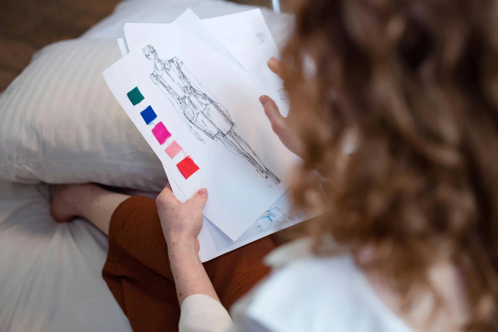 Fashion designer reviewing fabric samples and sketches for small batch apparel sourcing