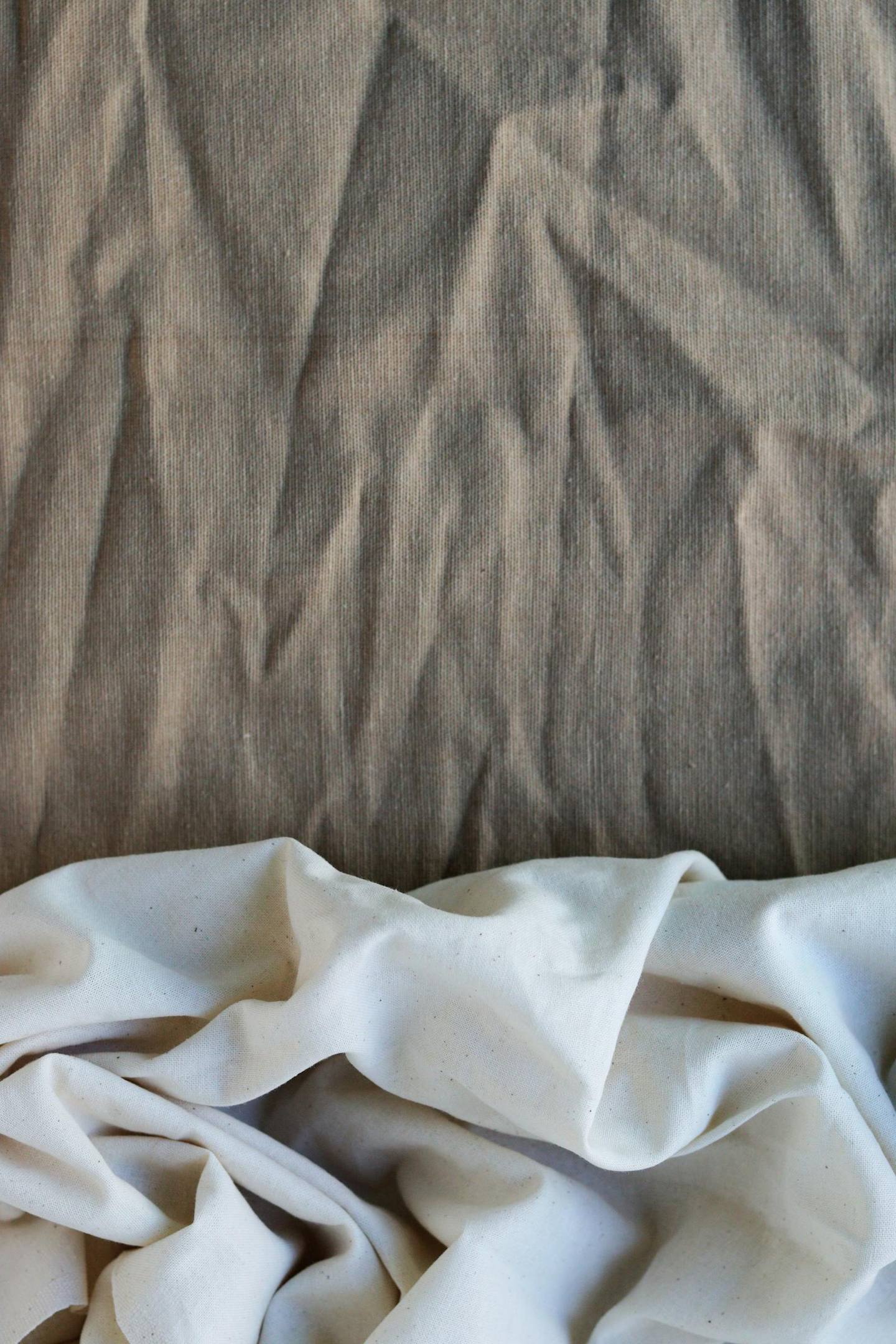 Layered natural linen and cotton fabrics in muted neutral tones.