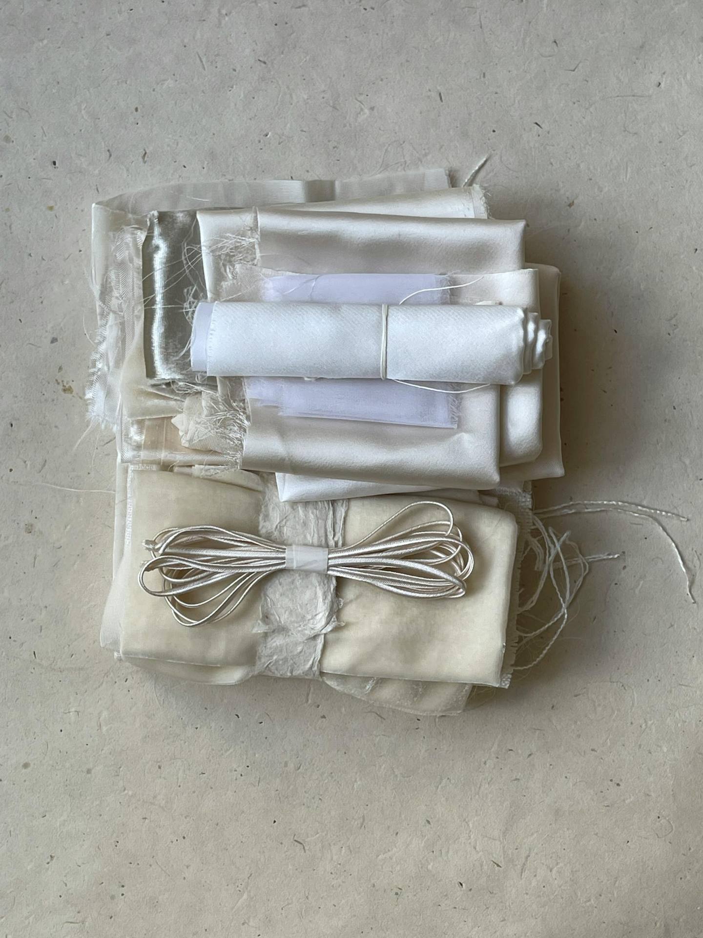 A neatly arranged set of white and neutral fabric swatches showing textile options.
