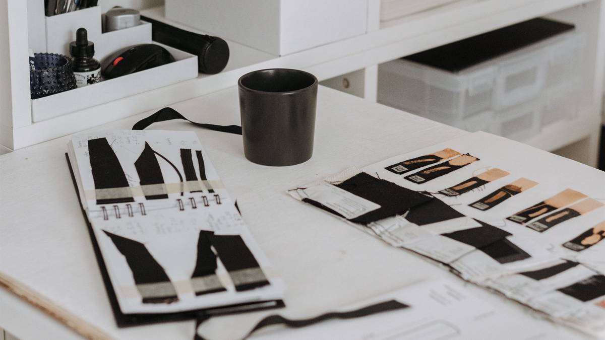 Fashion design worktable with garment sketches, fabric swatches, and label samples