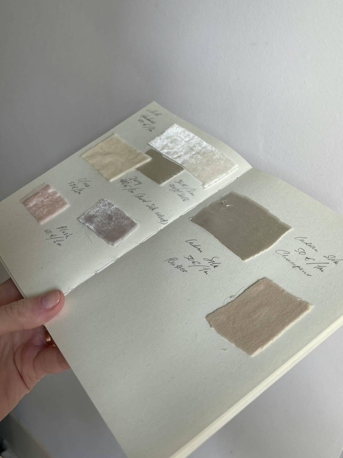 Fabric samples and handwritten notes organized in a notebook for structured supply-chain decisions.