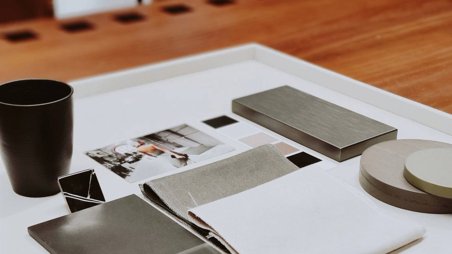 Neutral fabric swatches, material samples and color chips arranged on a design table