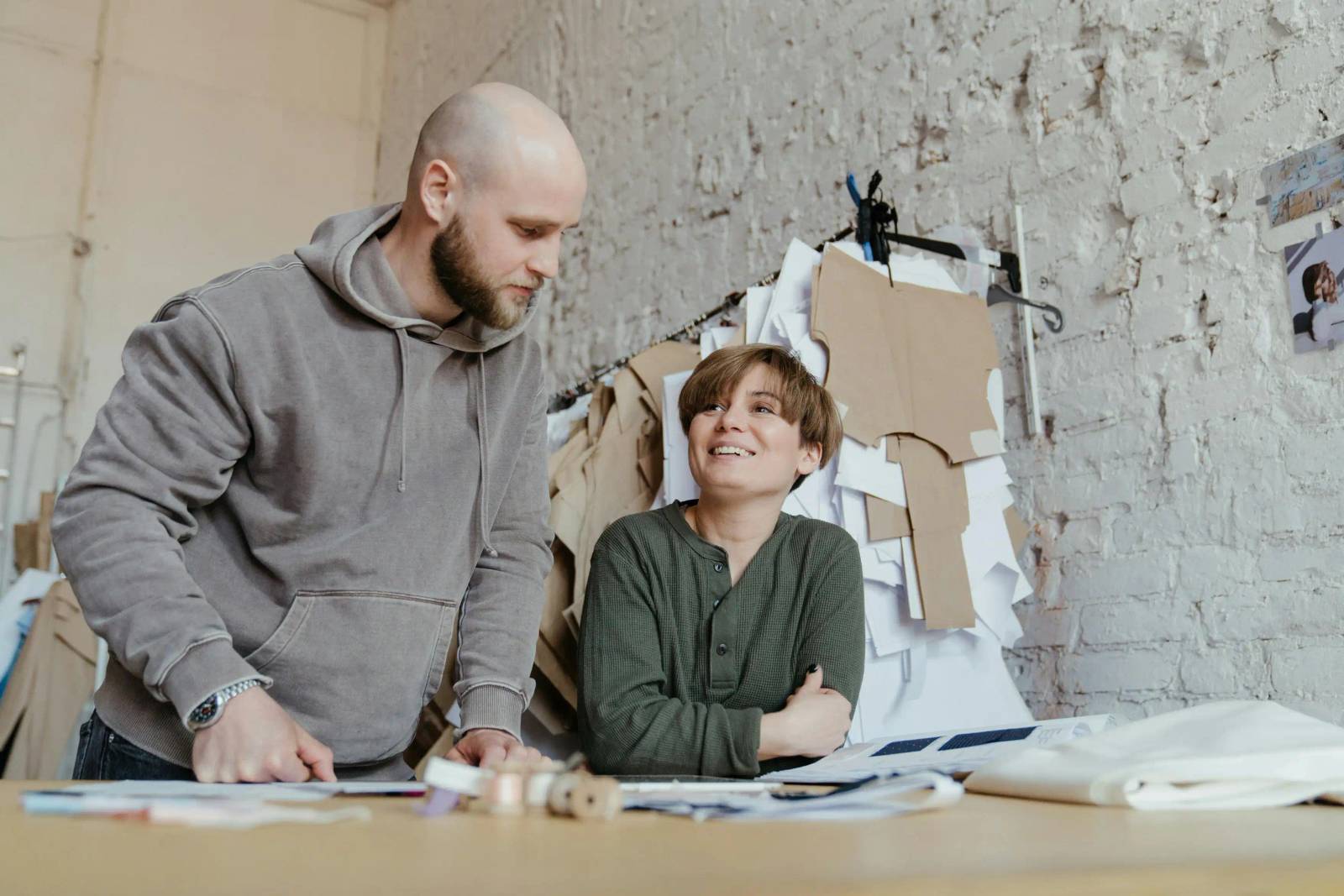 Two fashion designers coordinating patterns and sketches in an apparel production studio
