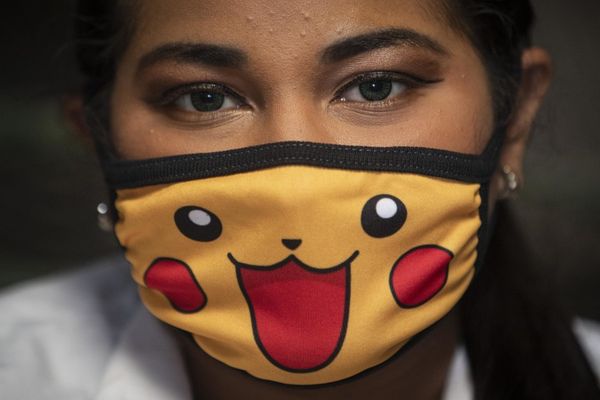 A women looks at the camera while wearing a mark with a smiling pikachu face on it.