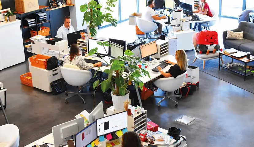 Aerial view of open modern office with people working at desks 