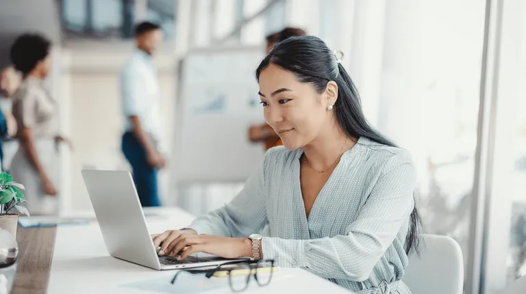A woman stilling at a desk working on a laptop