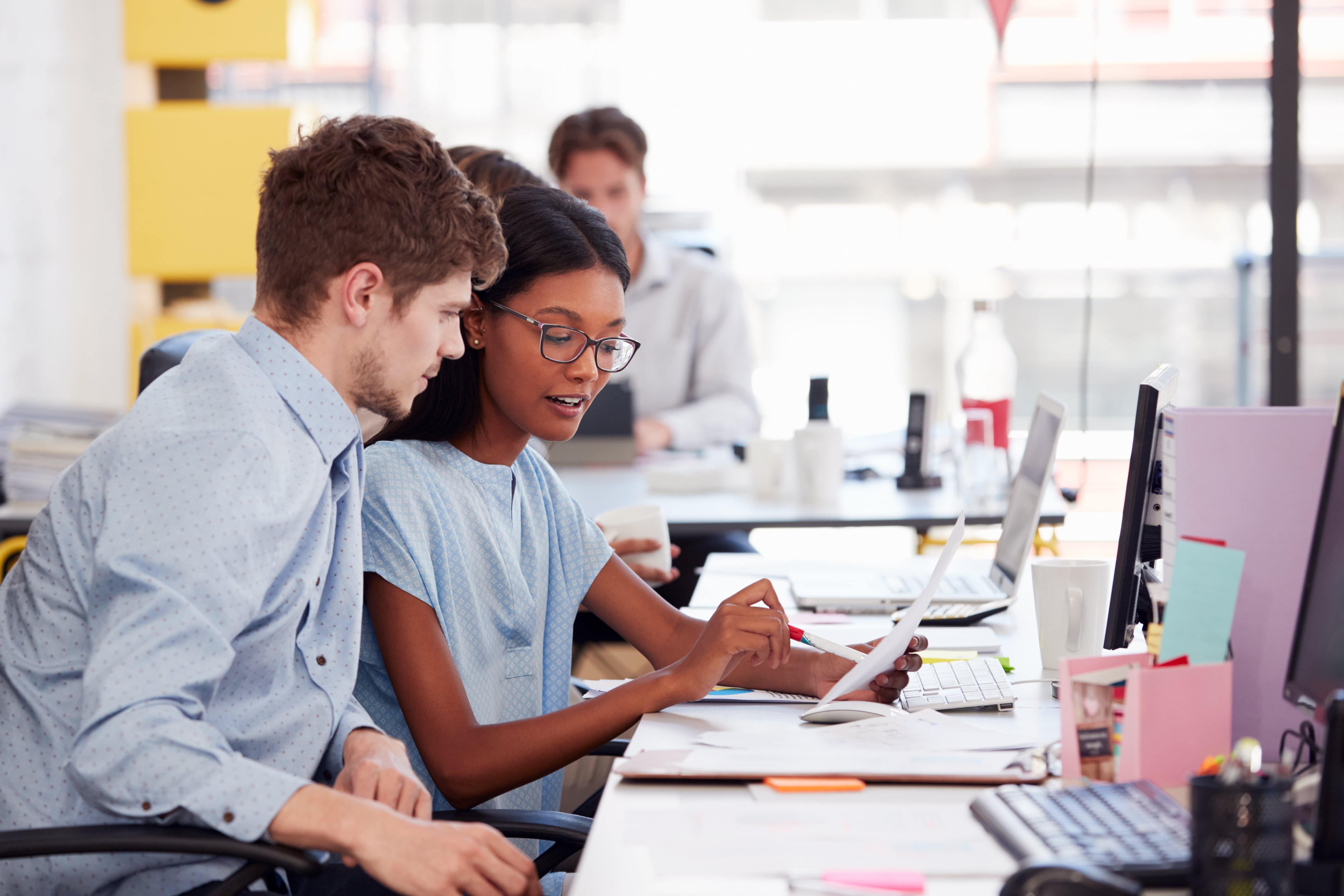 Man and woman discussing work at an office desk