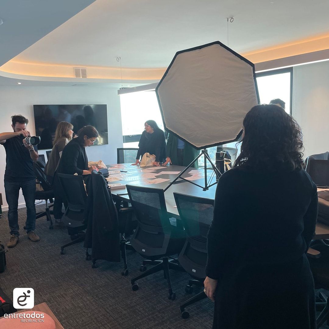 Un set de fotos con luz de estudio armado en una sala de reuniones, con gente alrededor